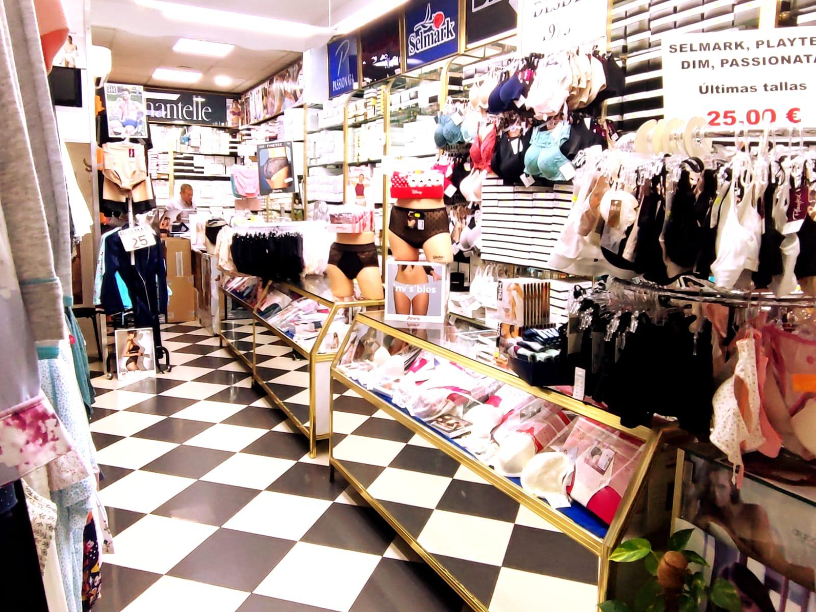 Interior de la tienda: suelo de damero, mostradores y perchas de ropa interior.
